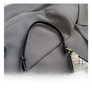 Detail of checkered pattern crescent bag with black leather handle and golden hardware