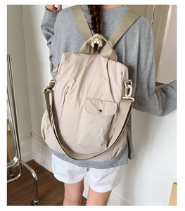 Detail showing versatile straps on beige nylon backpack for multiple carrying ways