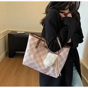 Détail du sac cabas à carreaux roses avec anses en cuir et breloque ours sur mannequin