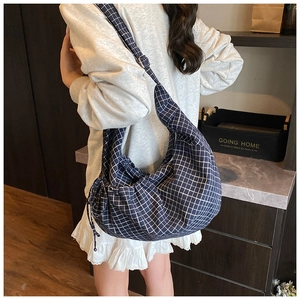 Close-up of blue checkered canvas crossbody bag with adjustable wide shoulder strap detail