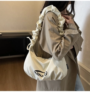Détail de la bandoulière en toile plissée et de l'imprimé Banau sur le sac crème