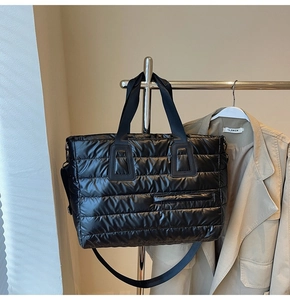 Détail du sac cabas matelassé noir avec large bandoulière sur support métallique