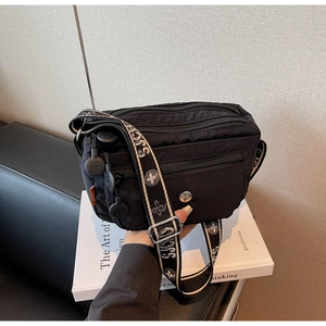 Close-up of black nylon crossbody bag with multi-zipper pockets and jacquard strap