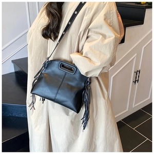 Detail of black leather tote bag featuring stylish side fringe and cutout handle