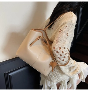 Detail view of beige tote bag with brown leather straps and cute elephant charm