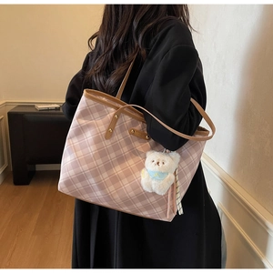 Détail d'un sac cabas à carreaux roses avec anses en cuir marron et pendentif ours mignon