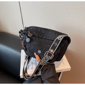 Detail of black nylon crossbody bag with multi-zipper layers and patterned strap