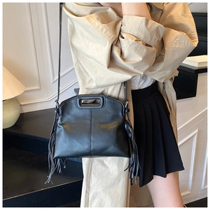 Detail view of black leather tote bag featuring stylish side fringe and contrast stitching