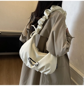 Détail du sac croissant en toile crème montrant la bandoulière froncée style nuage