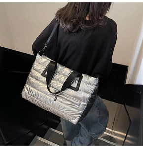 Détail d'un grand sac cabas argenté matelassé avec finition métallique et anses noires
