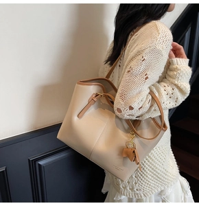 Detail view of beige leather tote bag with brown straps and cute pony charm