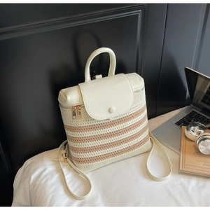Detail of woven straw backpack with white faux leather flap and gold zipper hardware