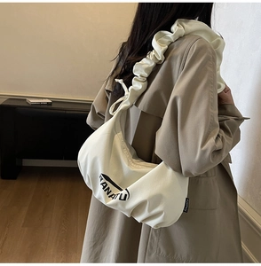 Détail du sac bandoulière en toile crème avec bandoulière plissée et logo RANATU noir