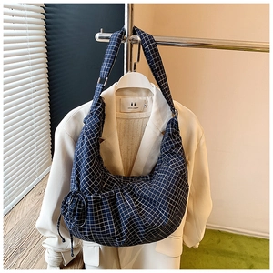 Detailed view of the blue and white checkered pleated crescent bag on a white blazer