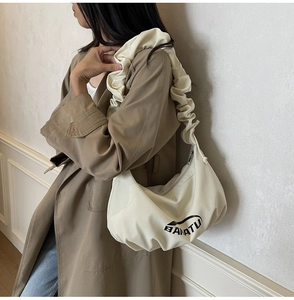 Vue détaillée du sac bandoulière crème en croissant avec bandoulière à volants