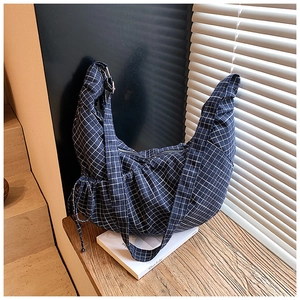 Close-up of navy blue plaid dumpling bag with drawstring detail and metal zipper