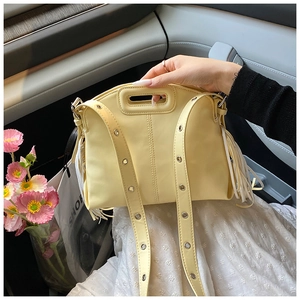 Detail view of cream tote bag with stylish side fringes and metal eyelet straps on car seat