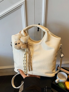 Chic beige crocodile embossed bucket bag with a cute plush dog pendant accessory