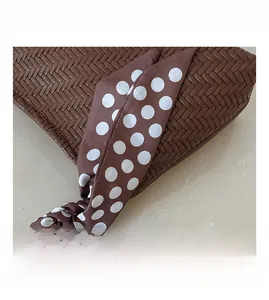 Detail of brown woven texture handbag with decorative polka dot silk scarf handle