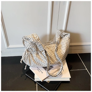 Detail view of the black and white checkered canvas shoulder bag with a drawstring closure
