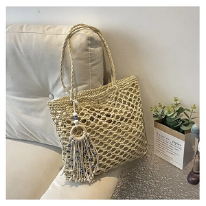 Close-up of bohemian woven tote bag with evil eye tassel and crochet mesh texture