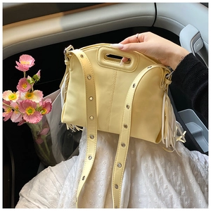 Close-up of yellow tote bag featuring fringe tassels and metal eyelet shoulder strap