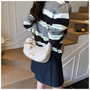 Detailed back view of a white checkered crescent bag with a plush rabbit charm and gold plaque