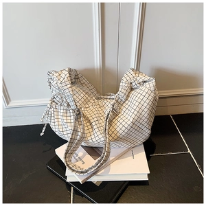 Detail of checkered canvas hobo bag showing drawstring side pocket and spacious design