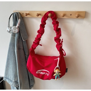 Détail du sac en toile rouge avec bandoulière plissée et pendentif poupée mignon