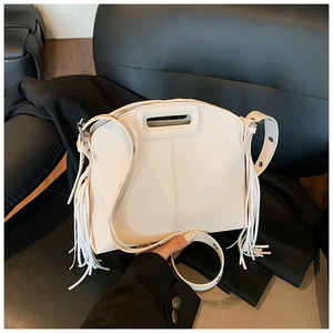 Detail of white leather tote bag with stylish fringe and top handle on a black chair