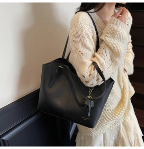 Close-up of black leather tote bag with elephant charm and fashion trend lettering detail