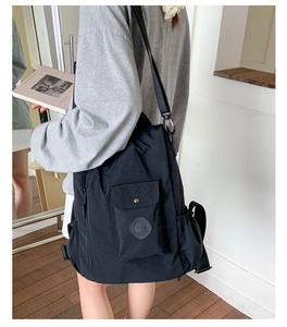 Detail showing high-capacity black nylon crossbody bag with side drawstring and adjustable strap