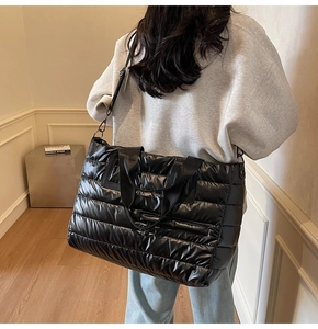 Détail d'un grand sac cabas matelassé noir en nylon brillant avec une bandoulière ajustable