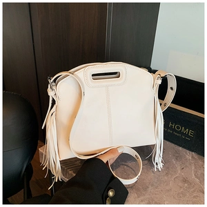 Detail of cream tote bag featuring long fringes and unique rectangular cutout handle