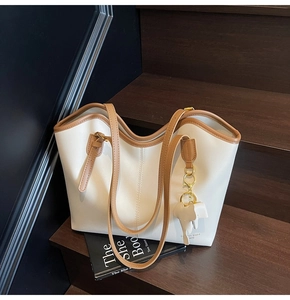 Detail view of large cream leather tote bag with brown straps and cute elephant charm