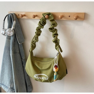 Détail du sac plissé vert avec logo Banatu et breloque en perles fantaisie