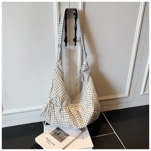 Detail of black and white checkered canvas hobo bag with drawstring texture and wide strap