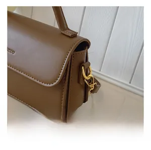 Detail of the brown PU leather shoulder bag featuring gold D-ring and metal clasp hooks