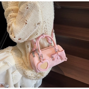 Detail of pink cylinder handbag with bow decoration and heart mirror on stairs