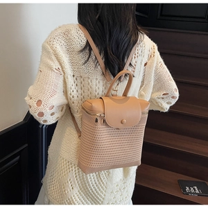 Detail view of khaki woven straw and leather patchwork backpack on a model back