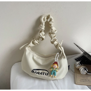 Détail du sac en toile blanc cassé avec bandoulière froncée et pendentif perle mignon