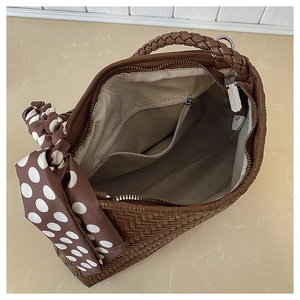 Detail of woven brown handbag showing herringbone lining and secure zipper pocket