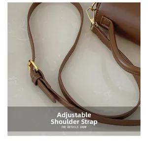 Detail of adjustable shoulder strap on brown leather bag with gold hardware