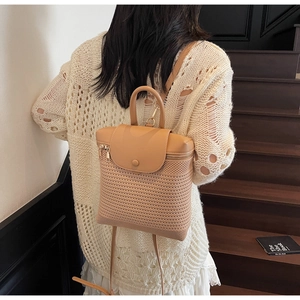 Detail of hand-woven straw backpack with contrast leather flap on model in rustic staircase