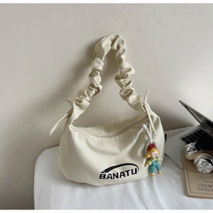Détail du sac croissant blanc cassé avec bandoulière plissée et charm cartoon