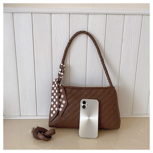 Detailed view of dark brown woven texture handbag with polka dot silk scarf detail