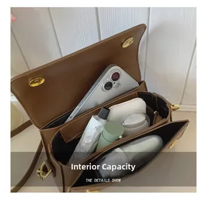 Detailed interior view of brown vintage shoulder bag showing storage for phone and makeup