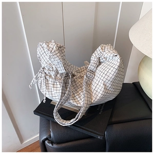 Detail of minimalist white grid crossbody bag with drawstring closure on a desk