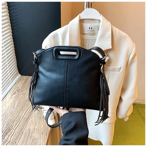Close-up of black leather tote bag with unique hollow handle and fringe tassel detail