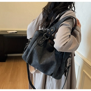 Grand sac cabas en daim noir anthracite avec rivets argentés porté par un mannequin